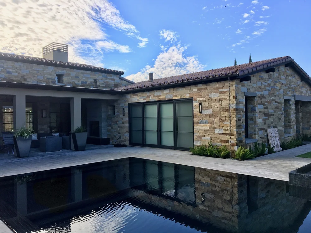 Honed Charcoal pavers and Napa Valley Estate ashlar veneer in split and natural faces around a home facade, patio, and pool.