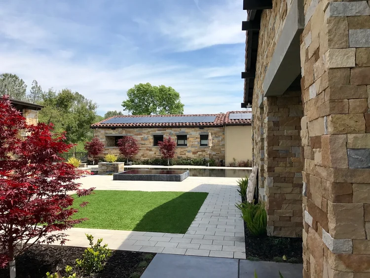 Napa Valley Estate ashlar veneer with honed Charcoal pavers across a home facade, patio, and pool surround.
