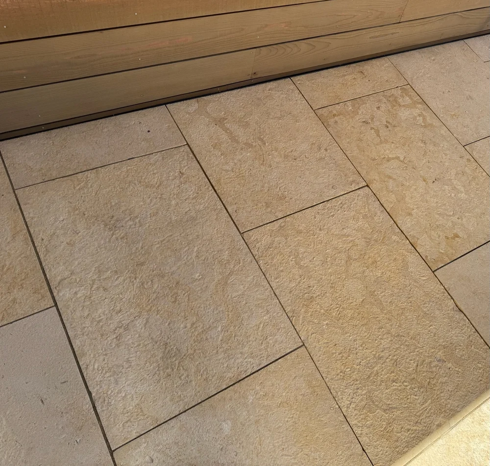 Cream dimensional pavers in a brushed finish laid in running bond across a patio.