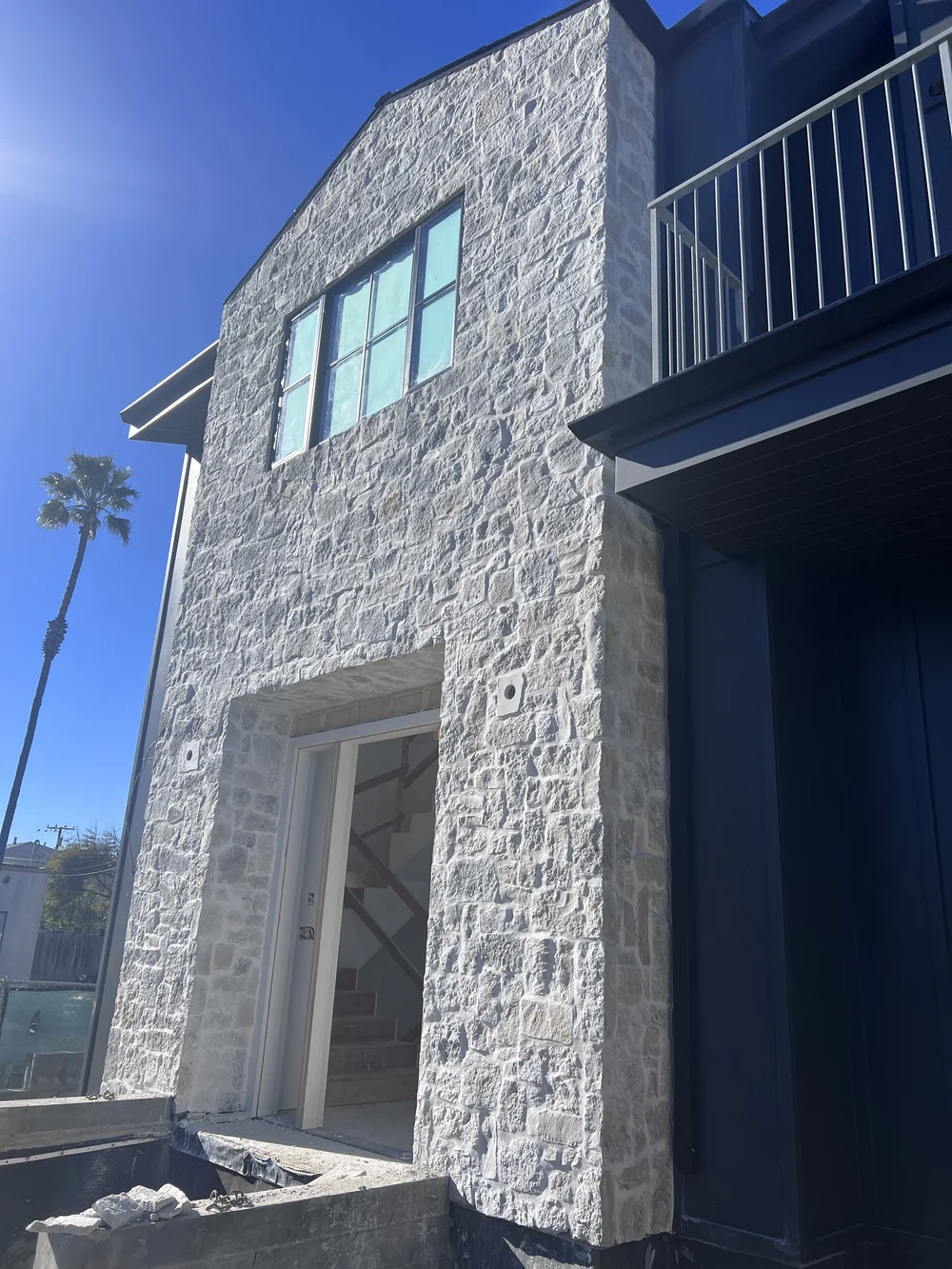 Tuscany Silver field veneer on a facade and entry in split and natural faces with overgrout joints.