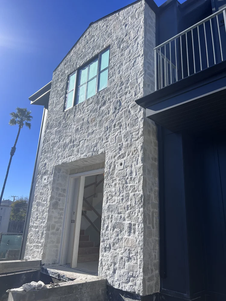 Tuscany Silver field veneer on a facade and entry in split and natural faces with overgrout joints.