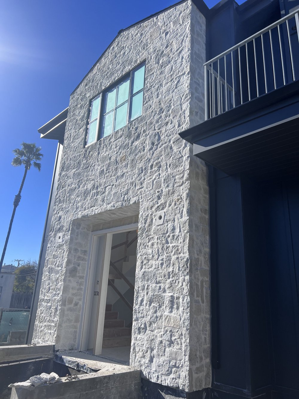 Tuscany Silver field veneer on a facade and entry in split and natural faces with overgrout joints.