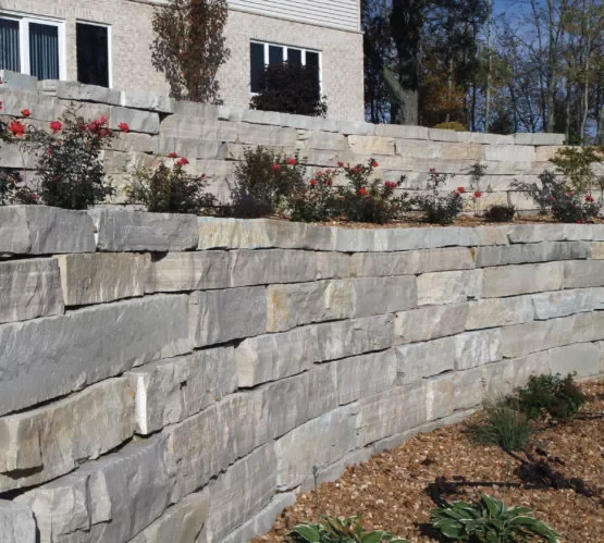 Fond du Lac in long coursed blocks builds a terraced retaining wall below a planted bank.