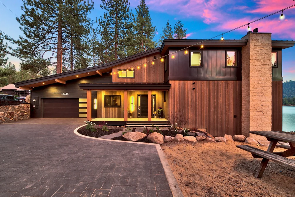 Cream ashlar veneer on a chimney rising through a modern lake-house facade at dusk.