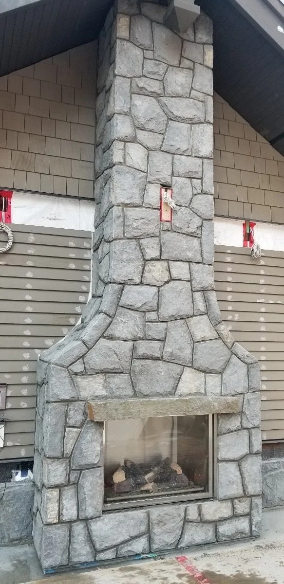 A Grizzly mosaic fireplace and chimney rise past lap siding above a linear gas firebox.