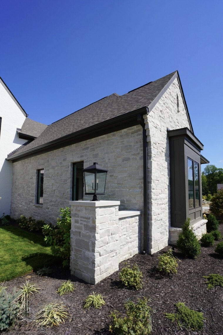 Byron ashlar veneer runs a steep gable end and turns down into a capped pier carrying a lantern.