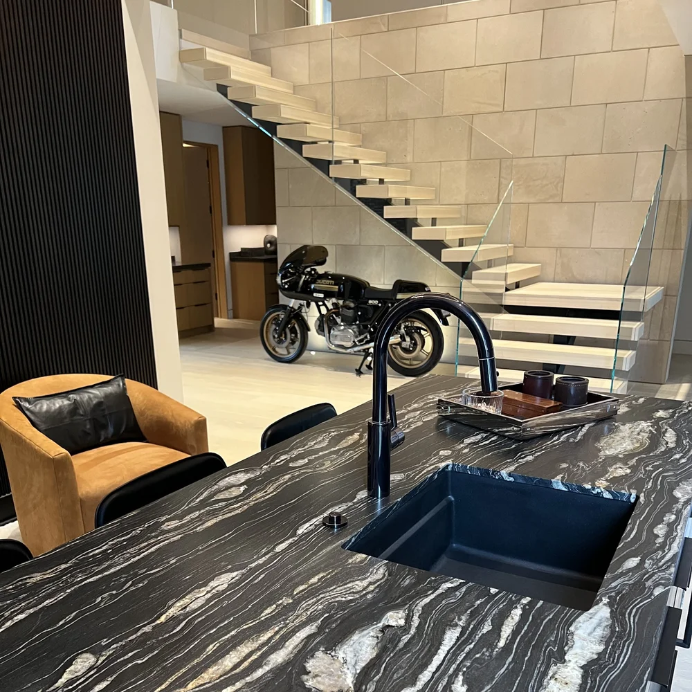 Indiana Limestone Buff panels wrap the stair wall of an open interior, behind a floating tread staircase and a glass rail.