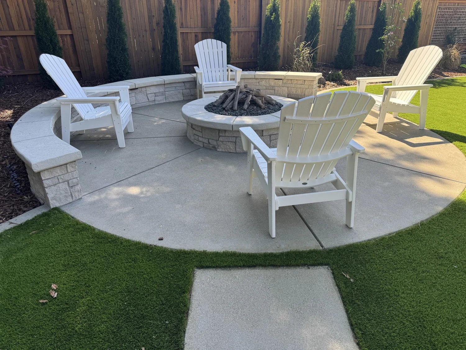 Adirondack chairs ring a Norway fire pit and its curved seat walls.
