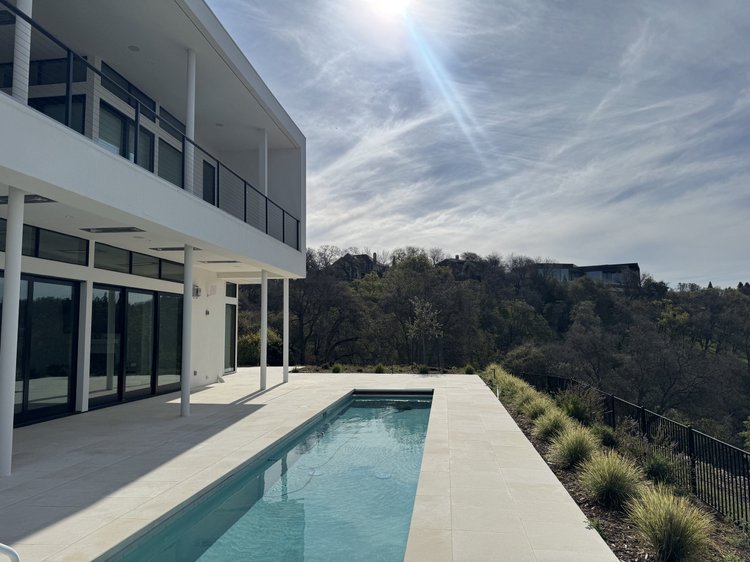 White honed paving and pool coping across a full backyard pool deck.
