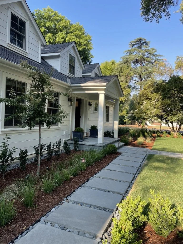 A Bluestone walk runs to the portico in large rectangular pavers, dark pebble filling the joints between them.