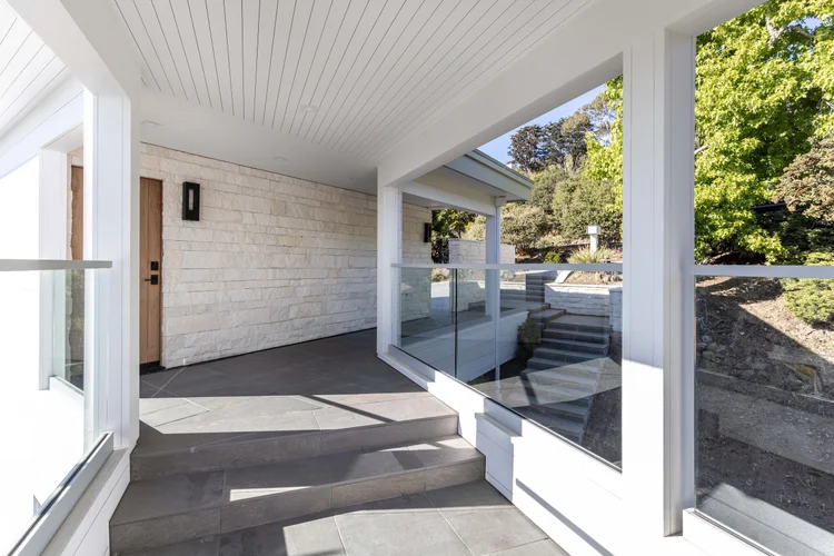 White coursed veneer with dry-stack joints alongside Bluestone natural-face pavers at a home entry and facade.