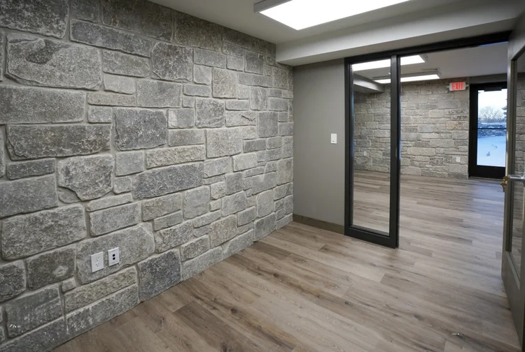 Fond du Lac in tumbled ashlar lines an interior wall beside sliding doors and a plank floor.