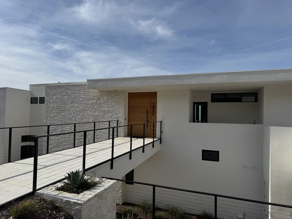 White ashlar veneer rising from white honed pavers at a home entry.