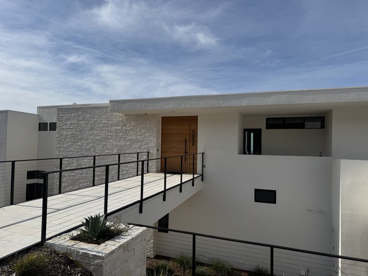 White ashlar veneer rising from white honed pavers at a home entry.