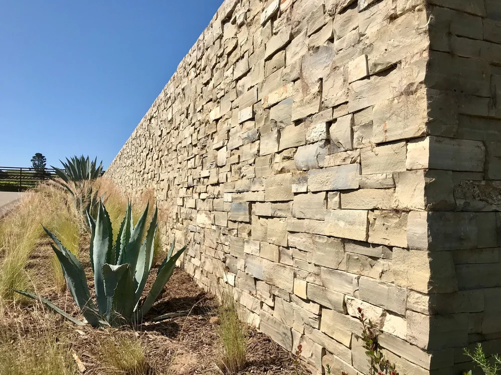 Dry-stacked Lompoc ashlar veneer running along a low wall.