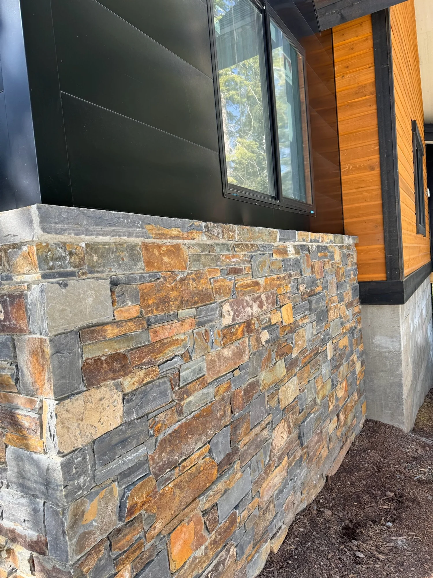 Split and natural face Belt River ledge veneer rising to a Belt River wainscot cap across a facade.