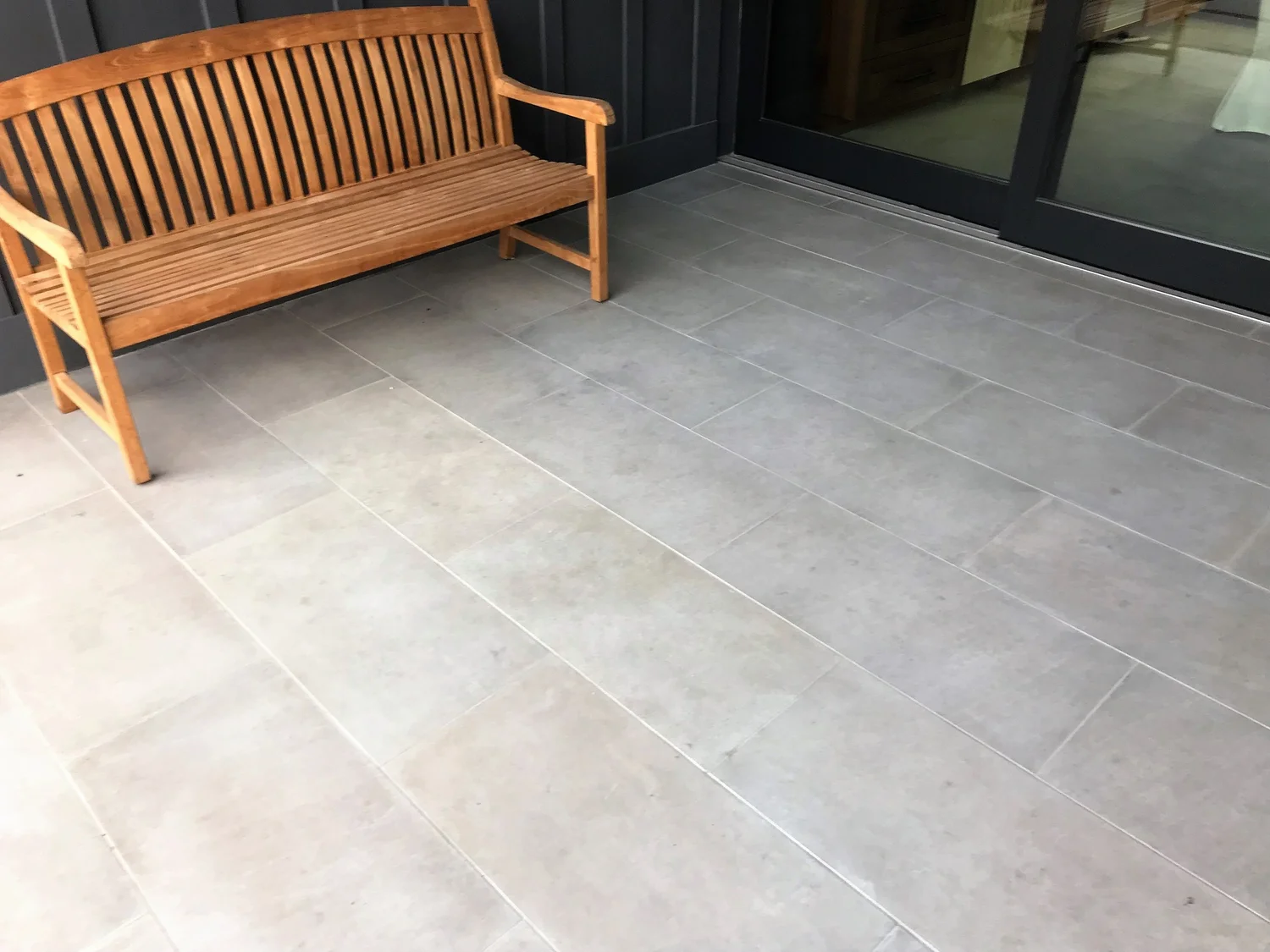 A teak bench sits on staggered Indiana Limestone Gray and Indiana Limestone paving beside the entry.