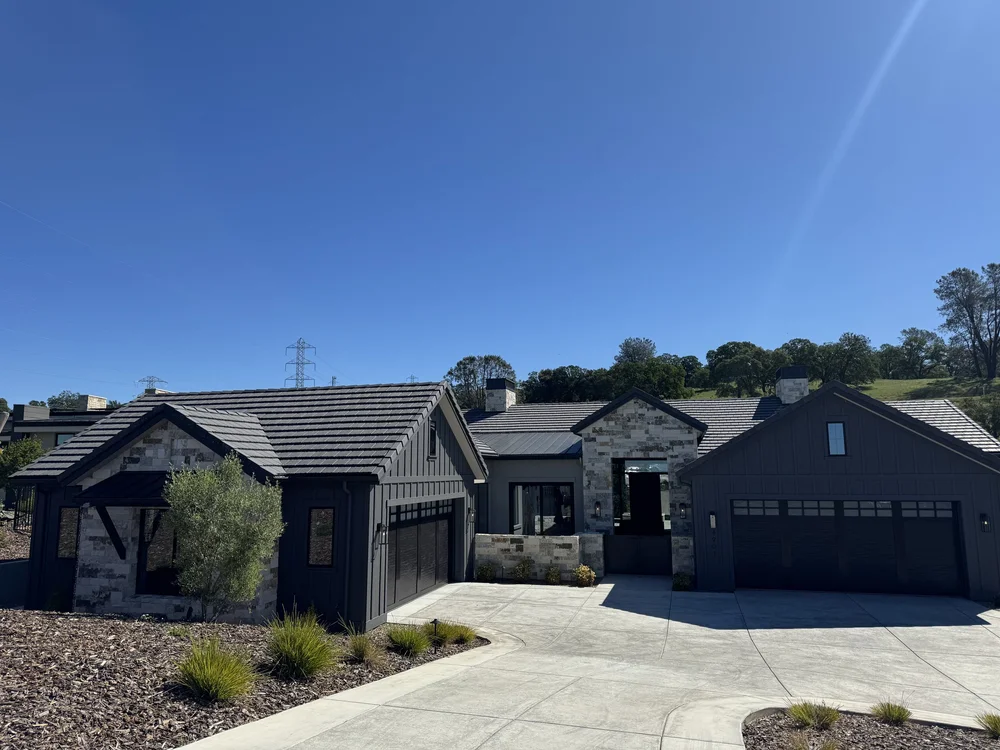 Blue picks out the entry pavilion and a wall panel across a dark sided elevation under a tile roof.