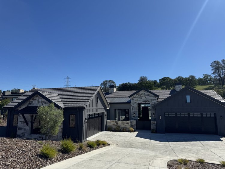 Blue picks out the entry pavilion and a wall panel across a dark sided elevation under a tile roof.