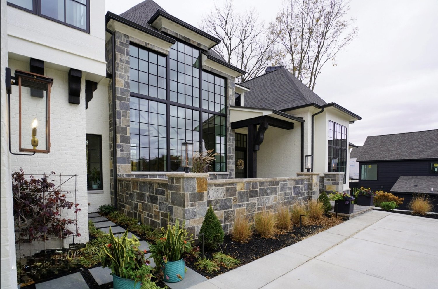 Graphite castle veneer forms the base wall beneath a tall window wall, grasses planted along its foot.