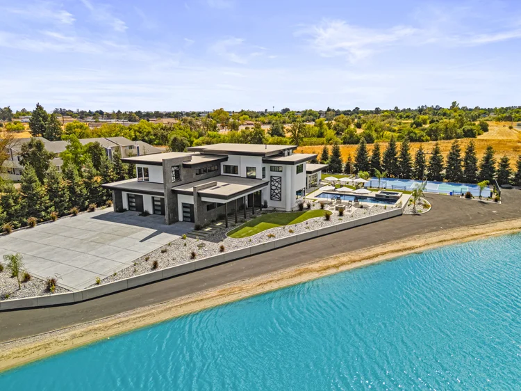 An aerial of the house and pool from over the lagoon, Black Basalt at its center.