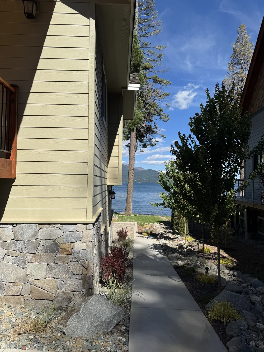 Gallatin River veneer beside a deck and stone walkway on the lake side.