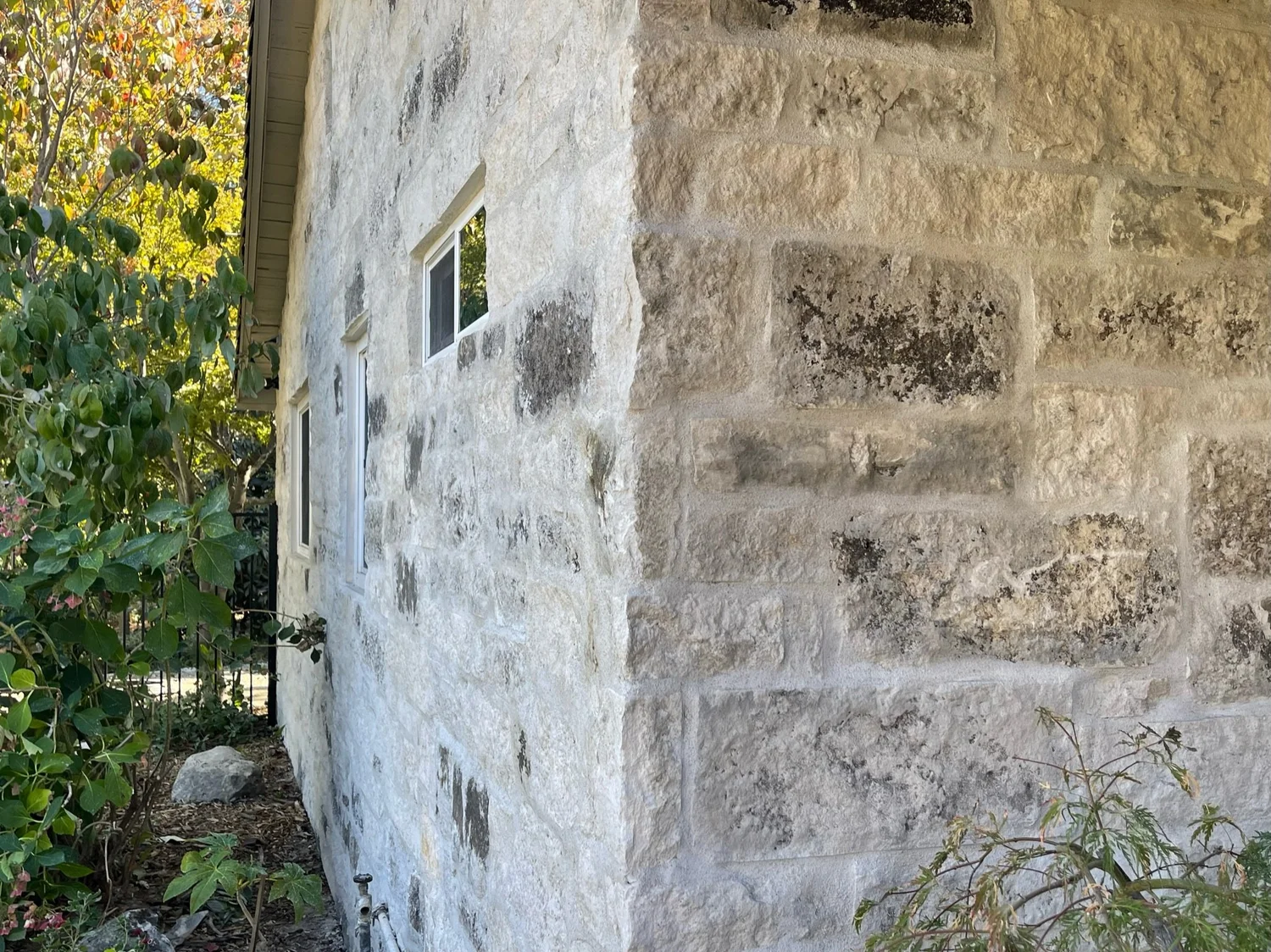 Blue turns the corner of the house in overgrouted courses, small windows punched into the wall.