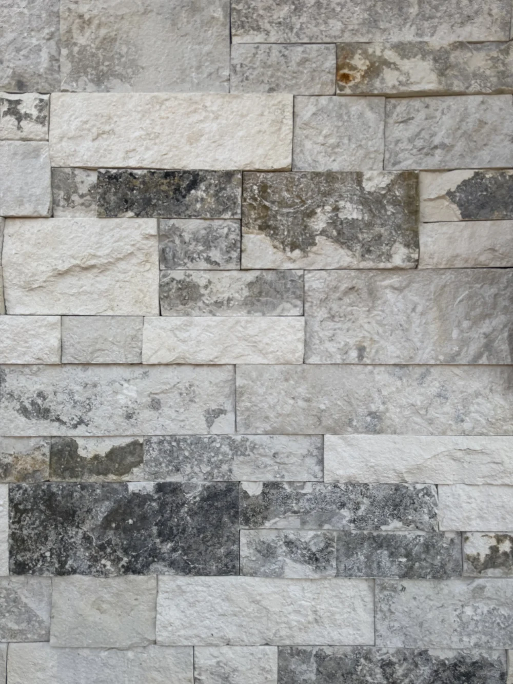 Blue in split and natural faces, cream and mottled gray courses stacked tight without visible joints.
