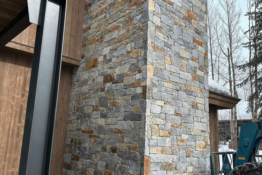 Yellowstone River veneer wrapping a chimney on a modern facade in split and natural faces.