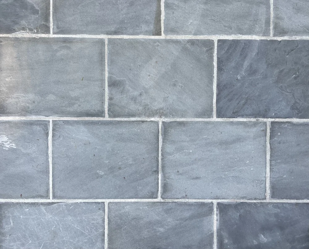 Bluestone dimensional pavers in natural cleft, blue gray units running in bond with tight pale joints.