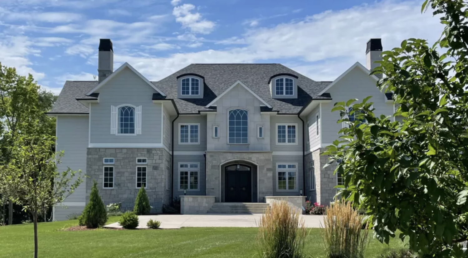 Fond du Lac castle veneer wraps the lower storey of a shingled house between white dormers.
