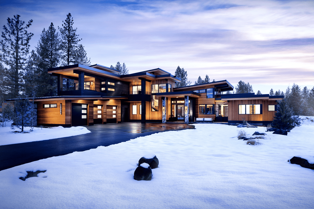 Charcoal veneer accents the entry and chimney of the home at twilight above a cleared drive.