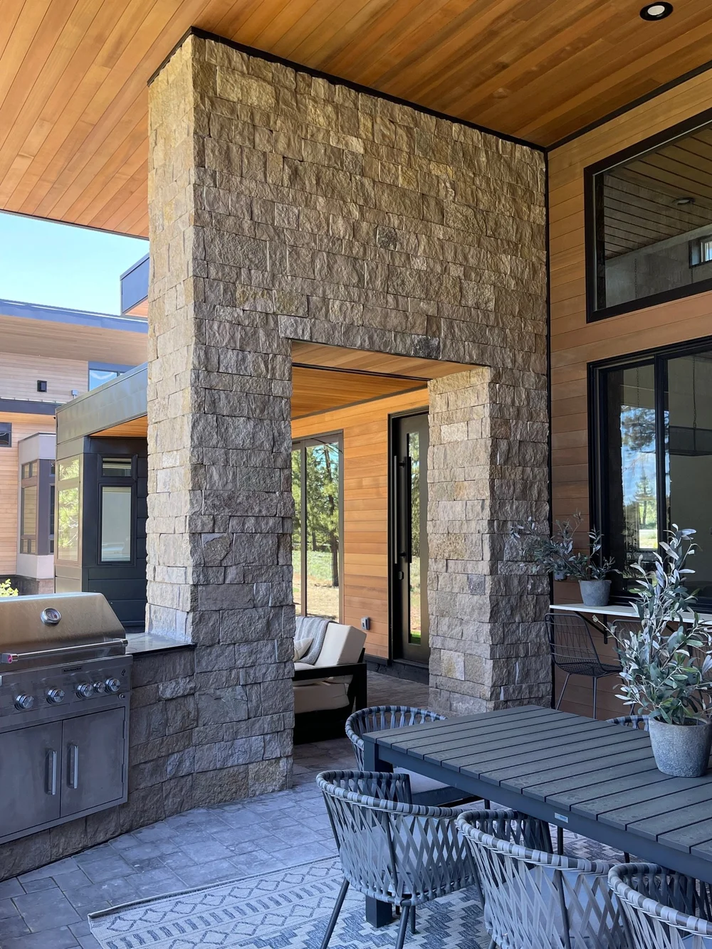 An Avalon-clad portal frames the entry, with the outdoor kitchen grill alongside.