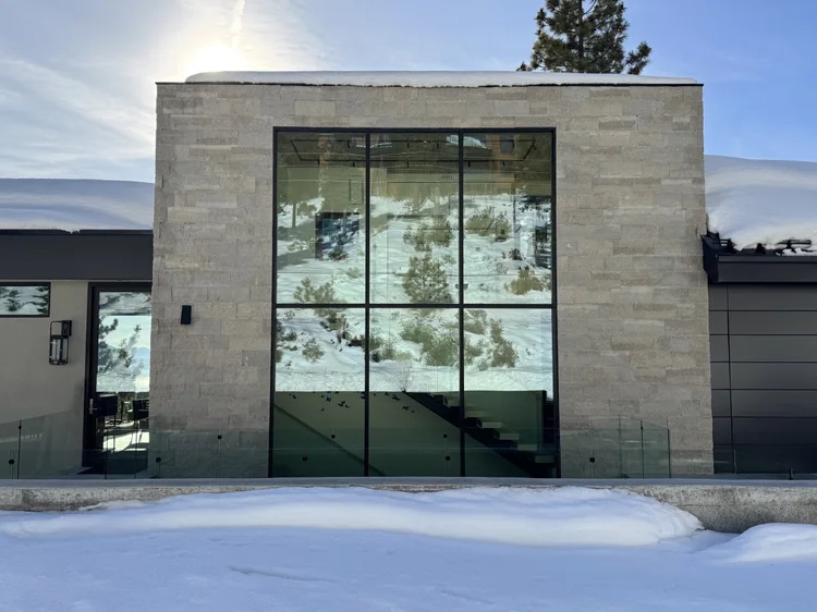 A tall Avalon-clad volume with a full-height window rises from the snow at Alpine.