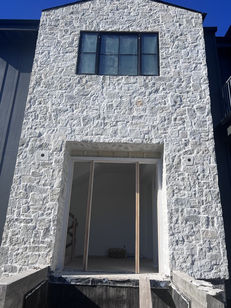 Tuscany Silver field veneer framing a facade entry in split and natural faces with overgrout joints.