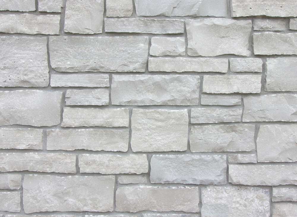 Byron ashlar veneer in split face, pale gray and cream courses of varied height with chopped ends and tight joints.
