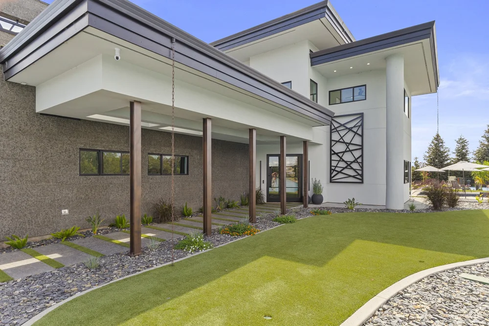 A Black Basalt wall runs the covered walk between timber posts, its dimensional pavers stepping through turf joints to the lawn.
