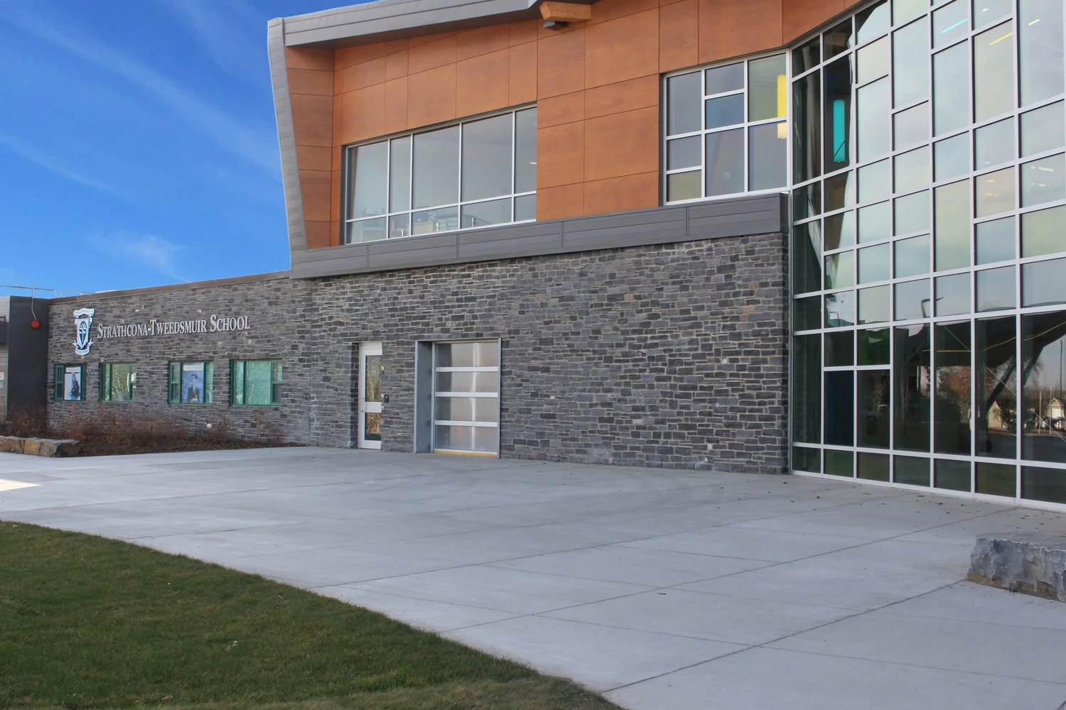 Black Rundle Stone forms the base course of a school elevation beneath timber cladding and a glazed stair tower.
