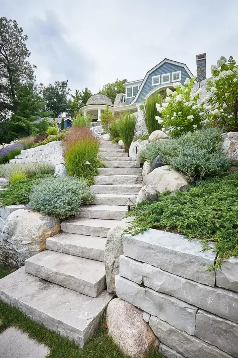 Fond du Lac treads climb a planted slope beside a stacked stone retaining wall.