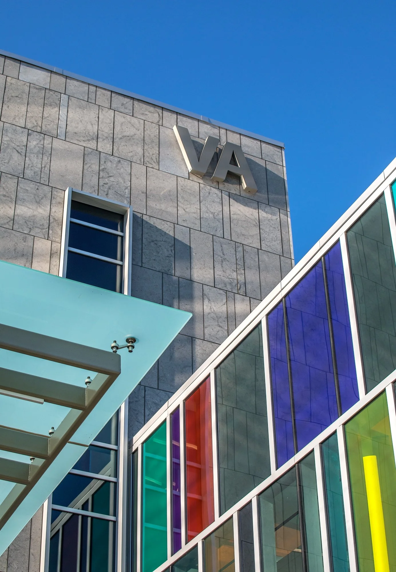 Large honed Plaza Gray panels clad a VA tower above a wall of colored glass.