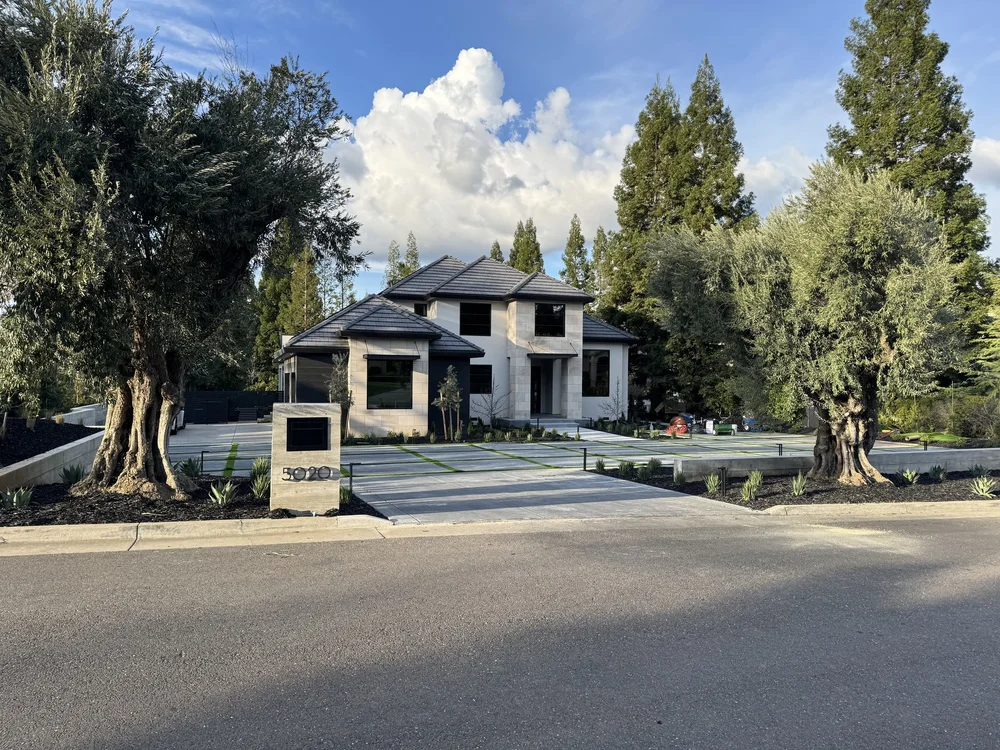 Indiana Limestone Buff panels face a two-story house set back behind mature olive trees.