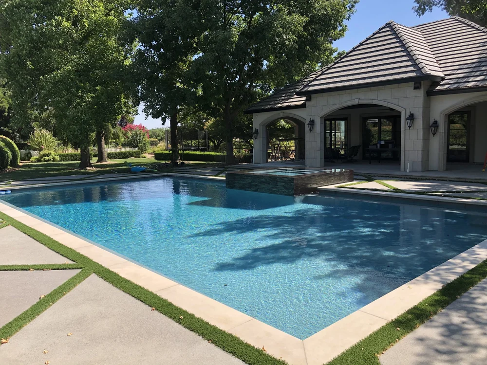 A pool runs to a pavilion of Indiana Limestone Buff, its arched openings framed in stone and its edge finished in coping.