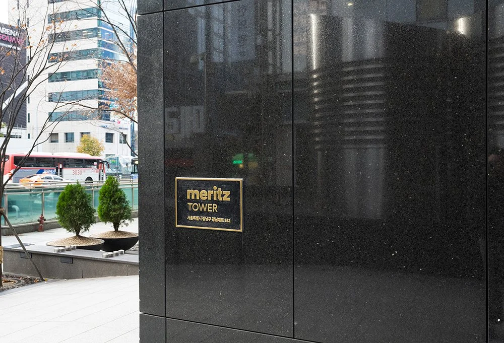 Polished Cambrian Black carries the gold Meritz Tower plaque on a pier at the street.