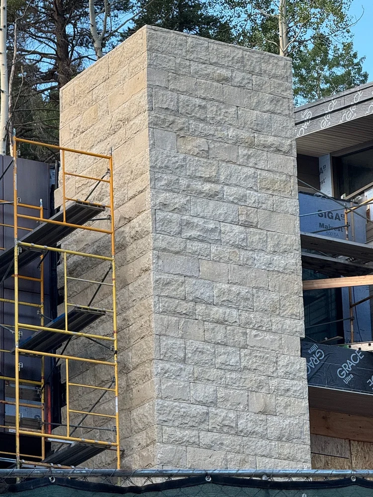 Buff laid as coursed veneer in split face with dry-stack joints on a facade.