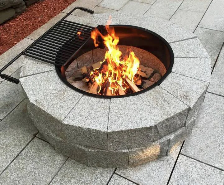 Fire burns in a Woodbury Gray pit ring set into a flamed paver patio.