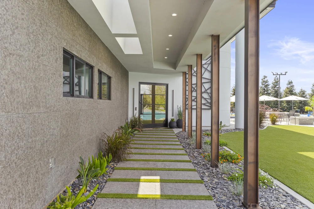 The Black Basalt entry wall carries flush windows above a walk of the same stone, dimensional pavers set in turf joints.