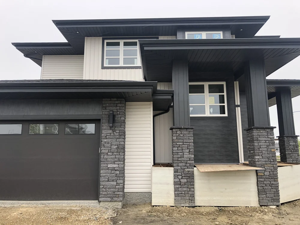 Silver Pearl wraps the garage surround and entry piers of a dark two story house.