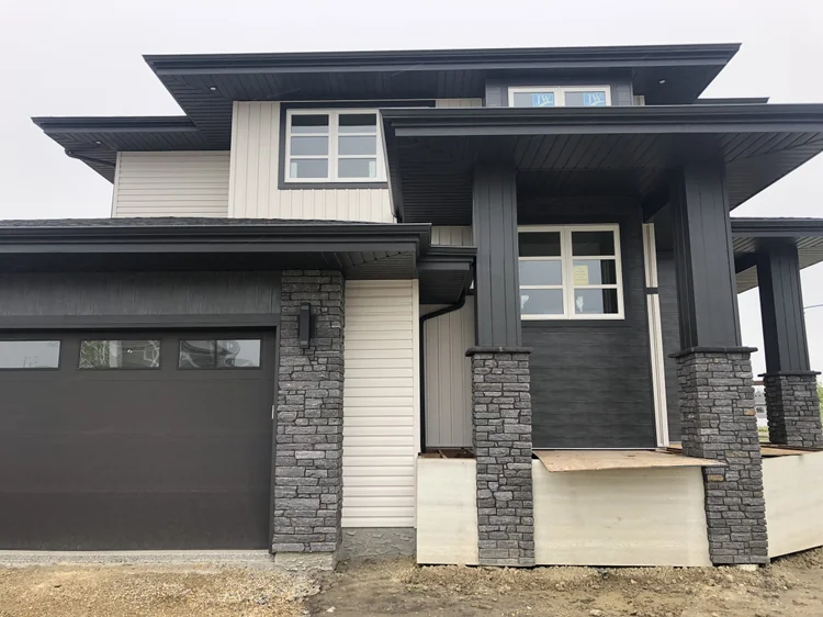 Silver Pearl wraps the garage surround and entry piers of a dark two story house.