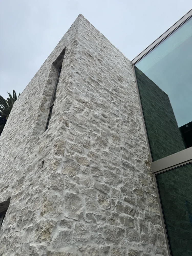 Tuscany field veneer wrapping a facade in split and natural faces with deep overgrout joints.