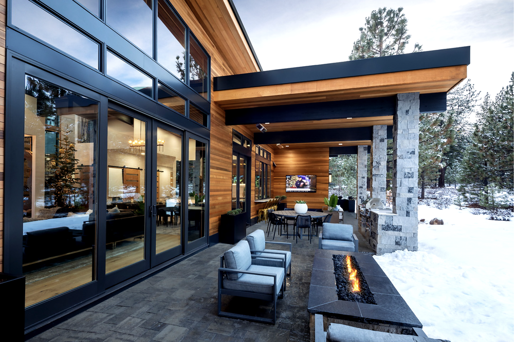 Charcoal veneer columns rise beside a linear fire feature, lit against the snow at dusk.